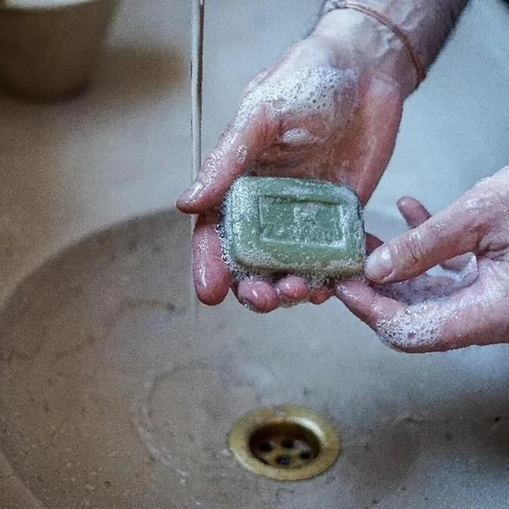 水道の下でオリーブ石けんを両手に持ち、泡立てている使用例