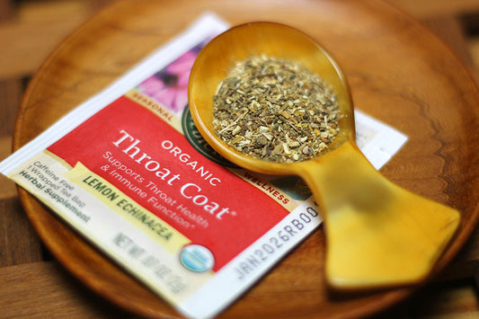 木製スプーンに盛ったハーブティーの茶葉と、Traditional Medicinals スロートコート レモン＆エキナセアのパッケージ