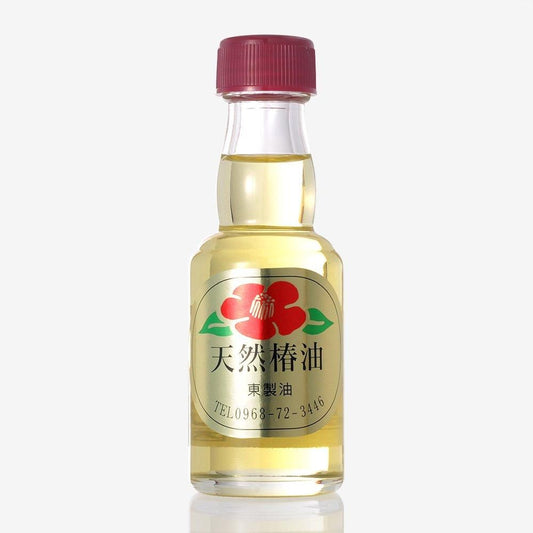 東製油の椿油55ml。黄色い液が見える透明瓶と赤いふた、椿の花の絵入り金色のラベル