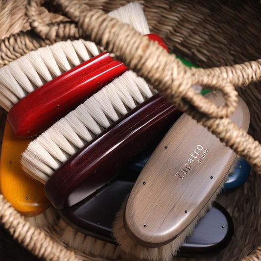 編みかごに重ねて収めたサパトロブエノの白い毛のポリッシュブラシ。赤、濃茶、灰色などの木部
