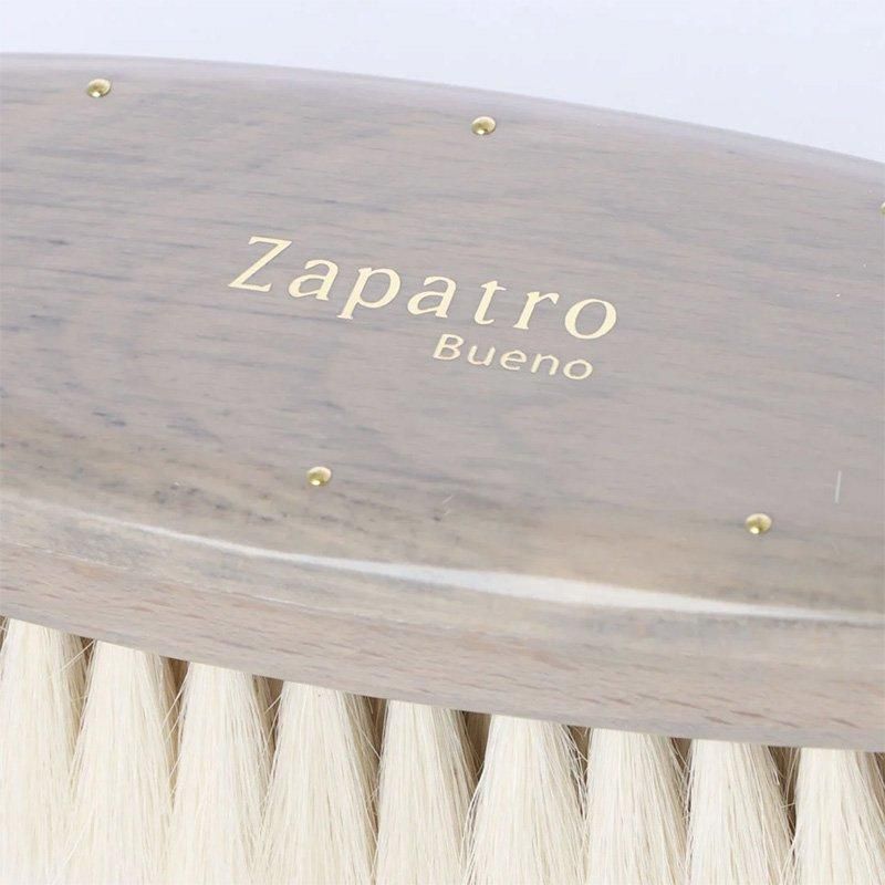 サパトロブエノの灰色のブラシの背面の拡大。金色のZapatro Buenoロゴと小さな金属の飾り