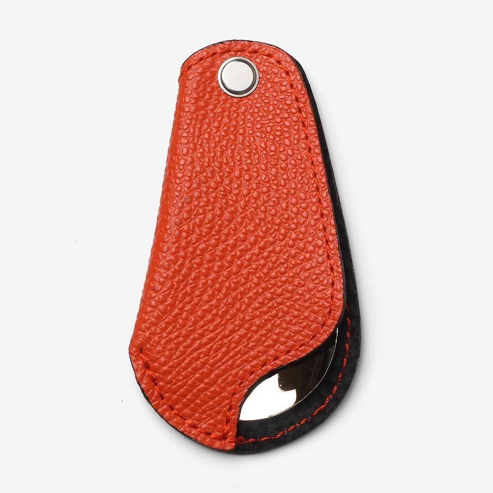サパトロのポケットシューホーン。オレンジの凹凸のあるカバーに折りたたんだ状態。銀色の留め具と靴べらの先端