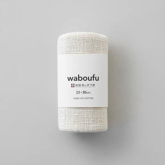 益久染織研究所 ガラ紡の和紡布23×85cm。生成りの布を巻き、waboufuの白い紙帯で包んだ状態